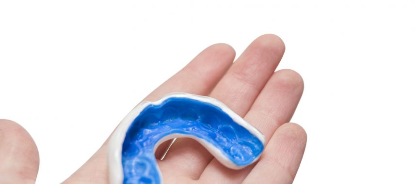 White custom sport mouthguard on a hand. Individual professional sport equipment.